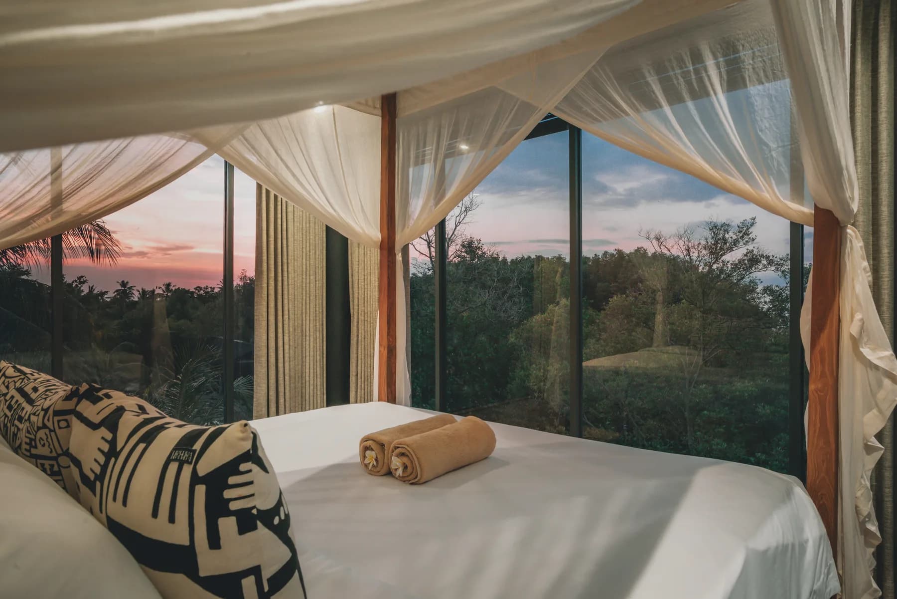 Lookout Loft bedroom at sunset with views through the palms
